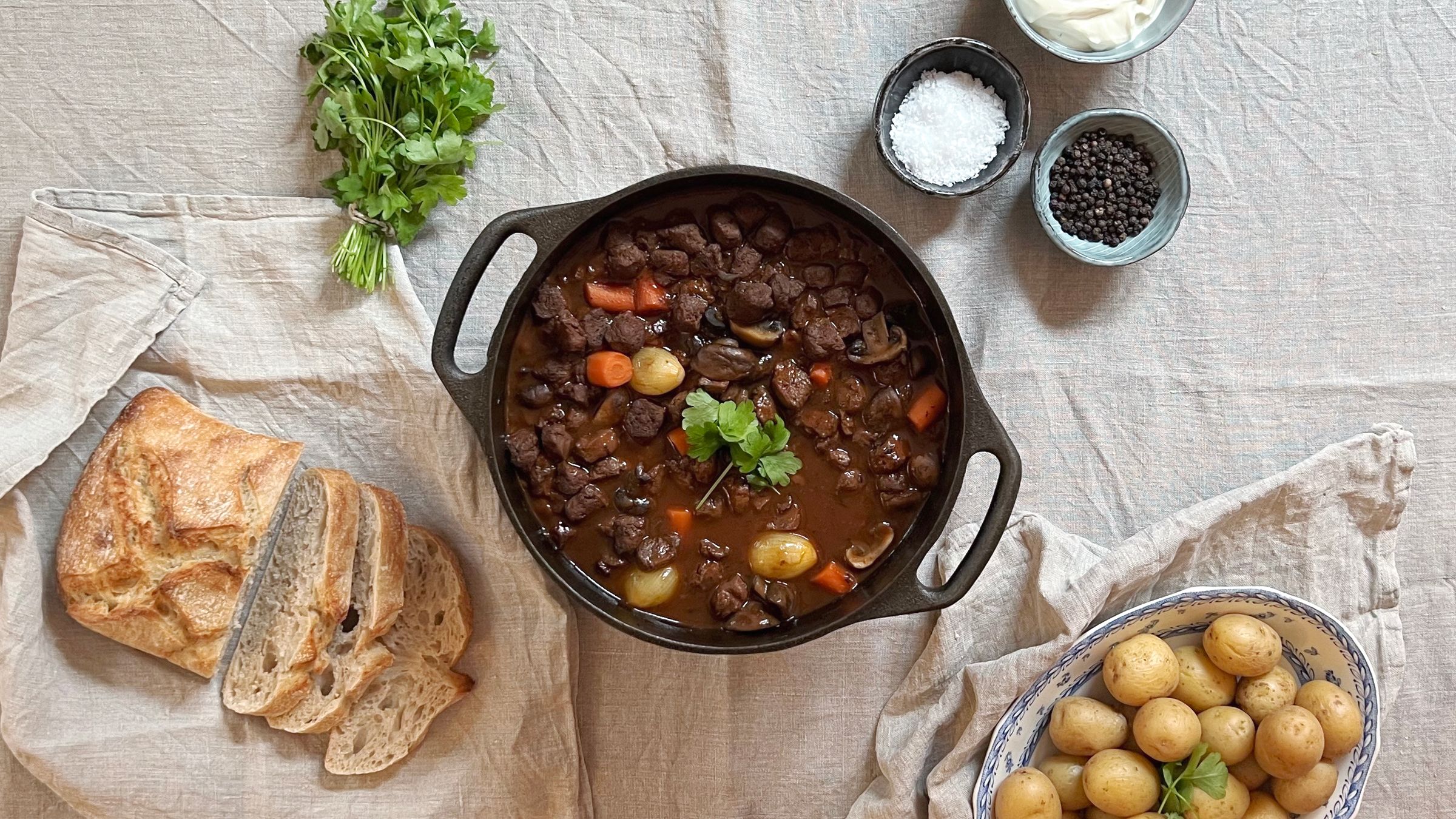 Gjutjärnsgryta med vegetarisk Beouf Bourguignon på ett dukat bord.